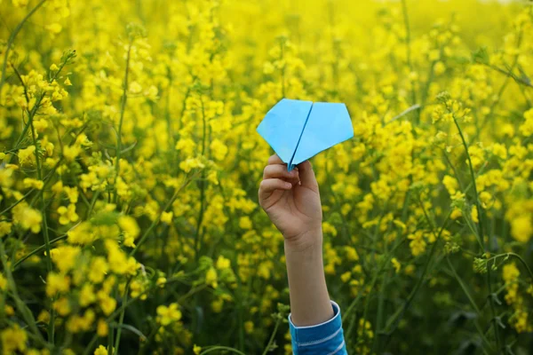 Avion en papier dans les mains des enfants sur fond jaune . — Photo