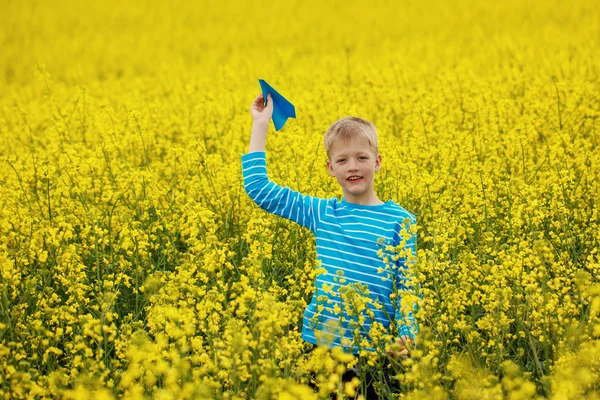Young boy with paper airplane against blue sky — Stock Photo, Image