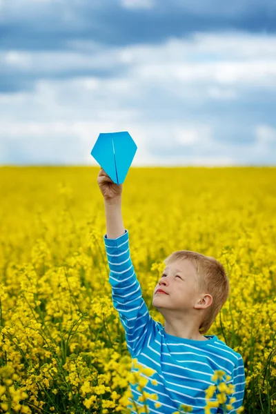 Young boy with paper airplane against blue sky — Stock Photo, Image