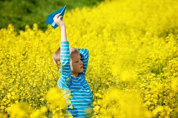 Garçon heureux tient dans la main avion en papier bleu sur une journée ensoleillée — Photo