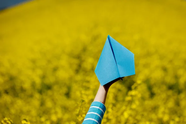 Aereo di carta in mani di bambini su sfondo giallo . — Foto Stock