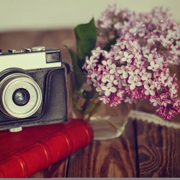 Cámara vintage y ramo de flores de primavera lila en bac de madera — Foto de Stock