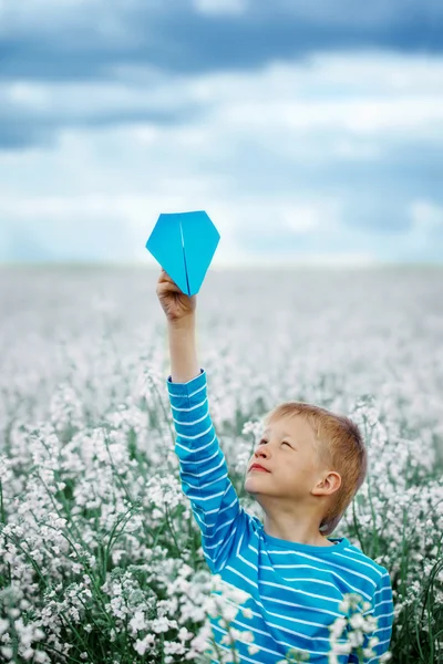 Jongen met papieren vliegtuigje tegen blauwe hemel — Stockfoto