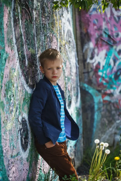 Fashion kid standing near a graffiti wall — Stock Photo, Image