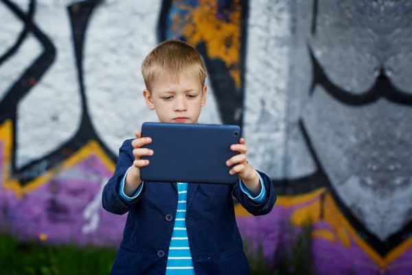 Malý chlapec včleněn do svého tabletu pro vzdělávání a hraní. — Stock fotografie