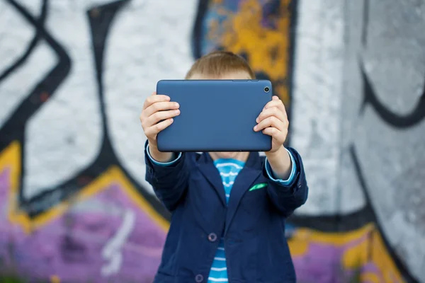 Kleine jongen opgenomen in zijn Tablet PC voor het opleiden en afspelen. — Stockfoto