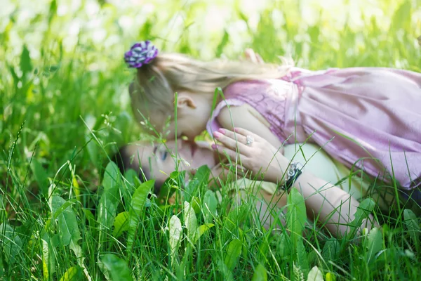 Κοριτσάκι με το ψέμα της μητέρας για ένα χόρτο αγκαλιάζω σε μια rasfokus, — Φωτογραφία Αρχείου