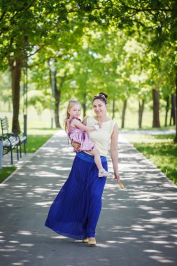 Mother with the daughter on hands walk in summer  park in sunny 