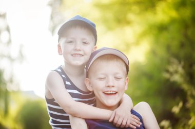 Two adorable little brothers laughing and hugging on warm and sunny day 