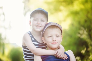 Two adorable little brothers laughing and hugging on sunny summer day 