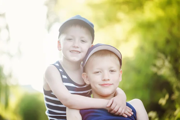 Dos adorables hermanitos riendo y abrazándose en el soleado día de verano —  Fotos de Stock