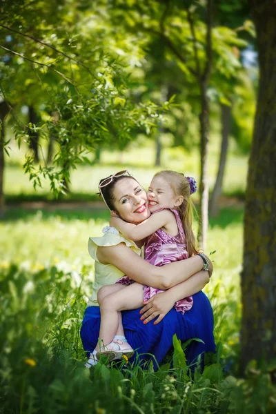 Happy family. Mother and  daughter lie on a grass I embrace  in — Zdjęcie stockowe