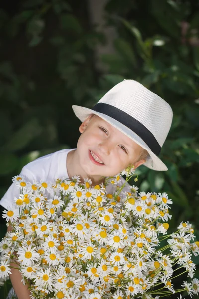 Ritratto adorabile ragazzo in un cappello con grande mazzo bianco di camomille — Foto Stock