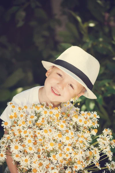 Портрет очаровательный мальчик в шляпе с большим белым букетом ромашки. Летом. Тонирование изображения — стоковое фото