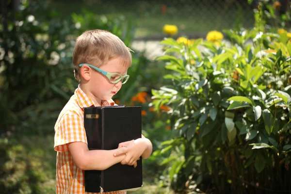 Portrait  little boy holding a big book on his first day to school or nursery. Outdoors, Back to school concept — Stock Photo, Image