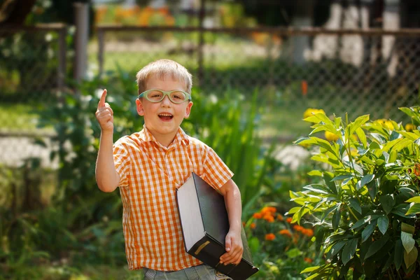 Porträt glücklicher kleiner Junge mit einem großen Buch an seinem ersten Tag in der Schule oder im Kindergarten. Draußen, zurück zum Schulkonzept — Stockfoto