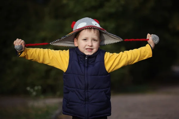 Happy little boy playing with cap  in  autumn park — Stock Photo, Image