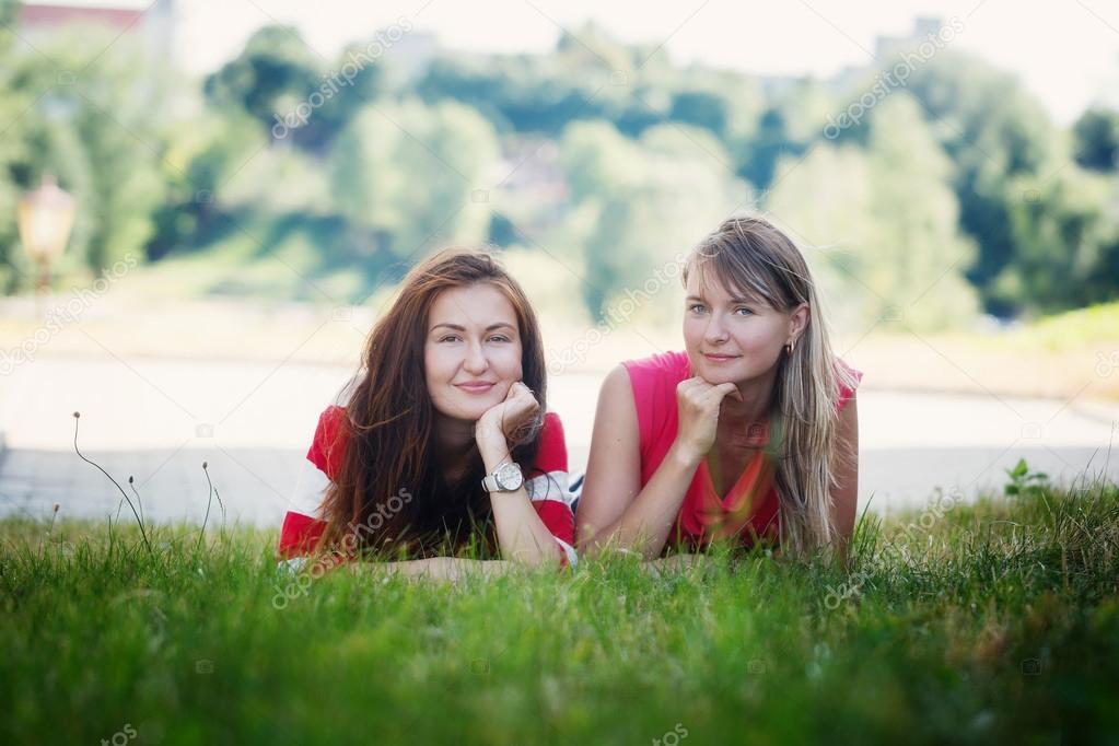 Two women friends laughing with  a green background