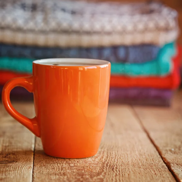 Rote Tasse Tee oder Kaffee mit einem Stapel gestrickter Pullover auf einem — Stockfoto