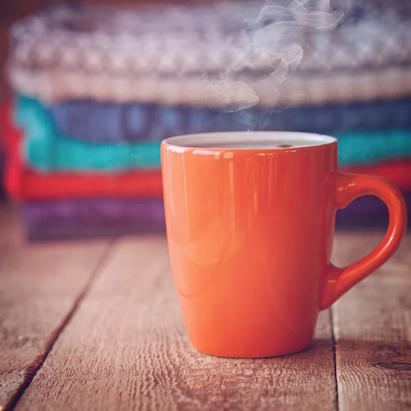 Rote Tasse Tee oder Kaffee mit einem Stapel gestrickter Pullover — Stockfoto
