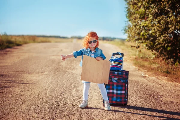 Little curly girl with suitcase  hitchhiking and standing about — Stock Photo, Image