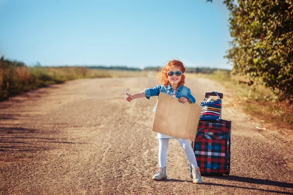 Little curly girl with suitcase  hitchhiking and standing about — Stock Photo, Image