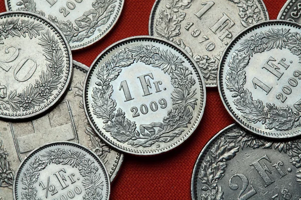 Monedas de Suiza sobre mesa roja — Foto de Stock