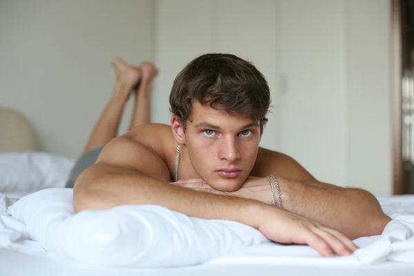 Jeune homme sexy sur un lit — Photo