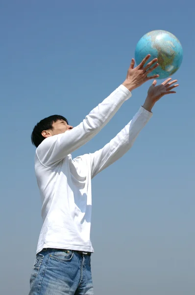 Jeune homme asiatique jouant avec un globe — Photo