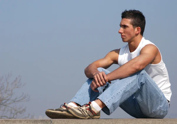Молодой сексуальный мужчина сидит — стоковое фото