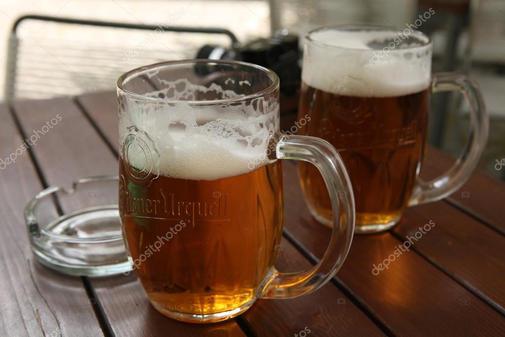 PRAGUE, CZECH REPUBLIC - MAY 13, 2014: Two mugs of traditional Czech beer Pilsner Urquell seen in a pub in Prague, Czech Republic.