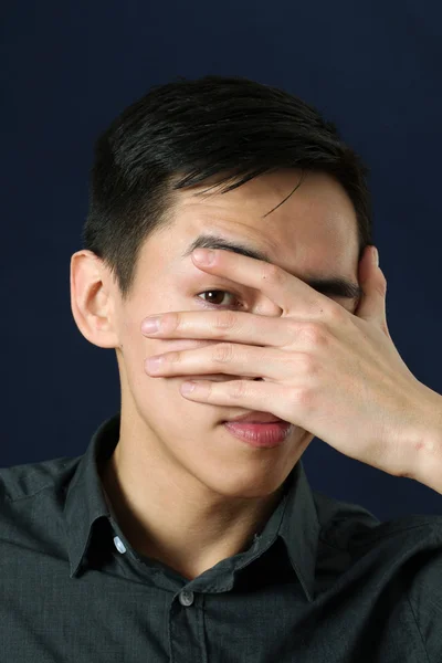 Asiatico uomo guardando attraverso la sua dita — Foto Stock