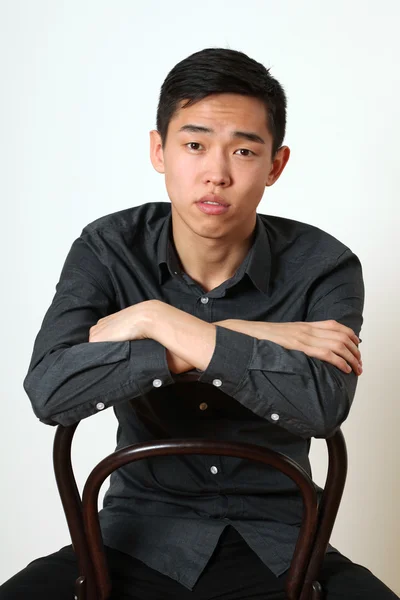Asiático homem sentado em uma cadeira — Fotografia de Stock
