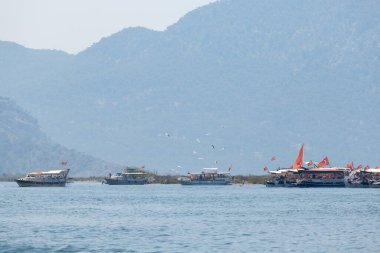 Dağların arka planında Türk bayraklı turizm tekneleri