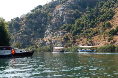 Arka planda dağ olan bir su kütlesi içinde küçük bir tekne.