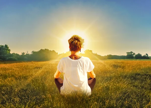 Женщина медитирует перед солнцем в поле — стоковое фото