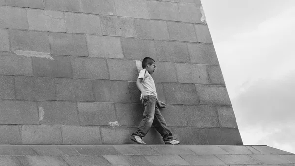 Niño caminando peligrosamente en la cornisa de un edificio — Foto de Stock