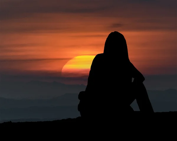 Femme assise à regarder le coucher du soleil — Photo