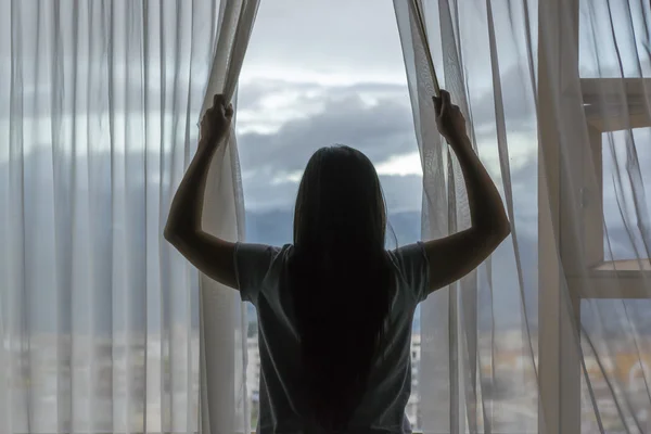 Ung kvinna öppna gardiner — Stockfoto