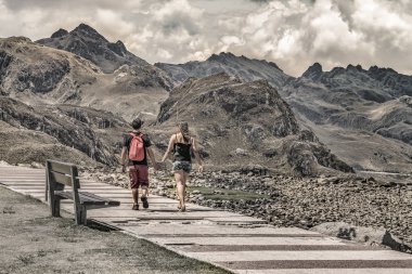 Kaldırım dağlar manzara arka plan ile yürüme Çift