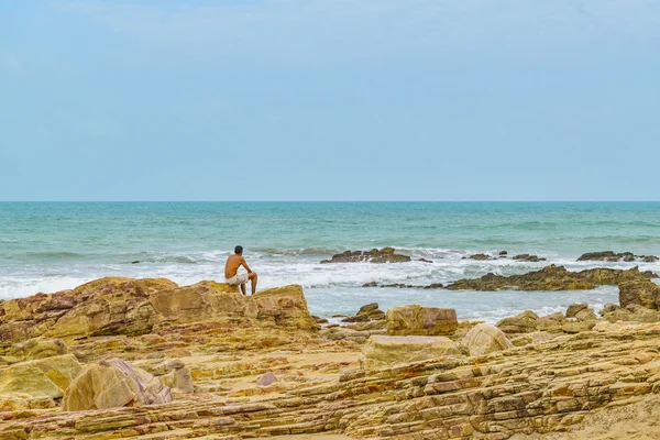 Muž sedící za skály na pláži Jericoacoara — Stock fotografie