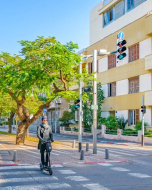 TEL AVIV, ISRAEL, Aralık 2019 Tel Aviv 'deki ünlü Rotschild Yayası' nda karşıdan karşıya geçen elektrikli kaykaylı adam.