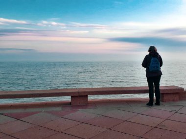 Arkaya bakan yetişkin kadın tek başına deniz kıyısında, Montevideo 'da, uruguay' da