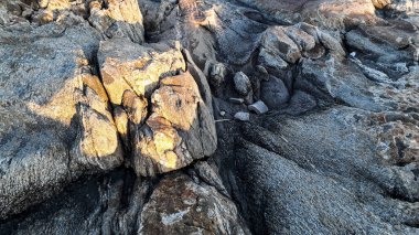 Sahilin arka planında büyük kayalıklar var.