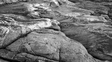 Sahilin arka planında büyük kayalıklar var.