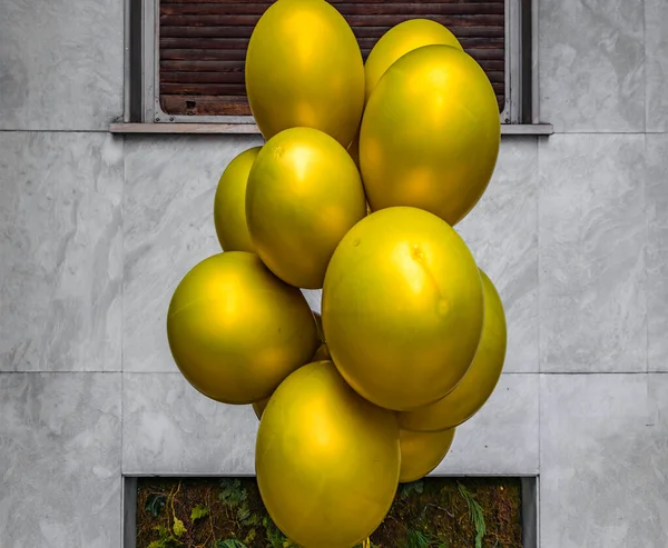 Duvarın Önünde Duran Bir Demet Altın Renkli Balon — Stok fotoğraf