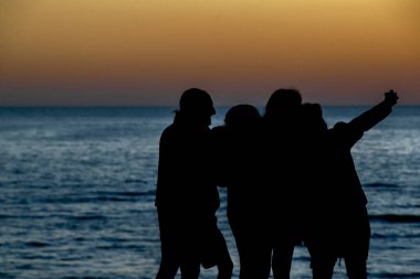 Sahil plajının, canelone bölümünün, uruguay 'ın önündeki gün batımı siluet sahnesi insanları.