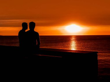 Yüksek kontrastlı gün batımı silueti sahnesi Erkek eşcinsel çift manzarayı izliyor, montevideo, uruguay