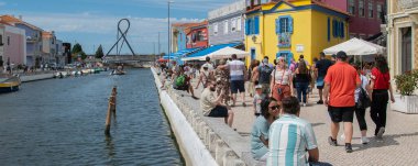 Aveiro, Portekiz: 15 Ağustos 2023: Aveiro Portekiz 'de mavi gökyüzü altındaki renkli binalar boyunca yürüyen kalabalığın geniş bir görüntüsü