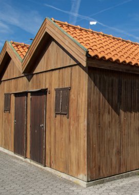 Front view of traditional wooden fishing sheds at Costa Nova beach Aveiro Portugal under clear blue sky showing rustic textures and coastal heritage